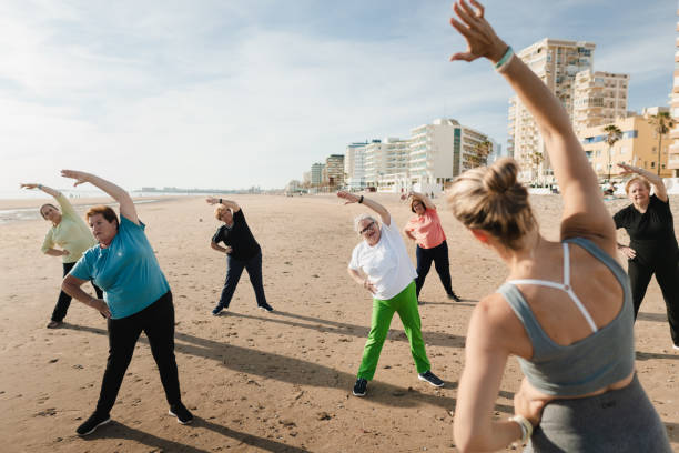 istock Group of senior women doing stretching exercises on the beach with their trainer 2187731469