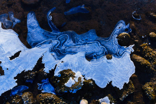 Icy Frost Covered Rocks River Nature Detail - Frozen ice coated with frost with rocks and warm sunrise light complemented by cool winter shadows. Nature scenic along Eagle River on very cold morning.