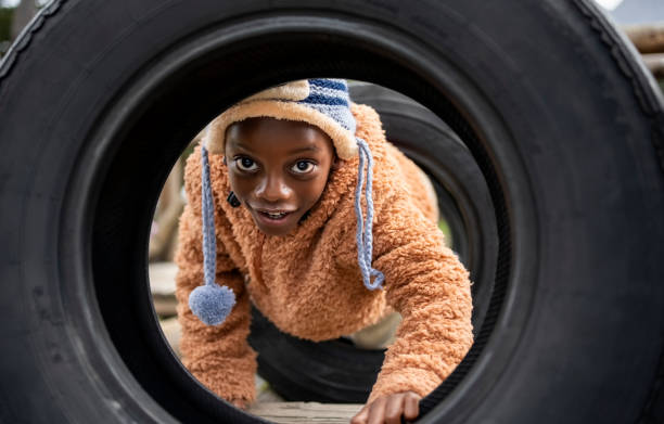 Cute small boy playing on a tyre tunnel at the playground and having fun