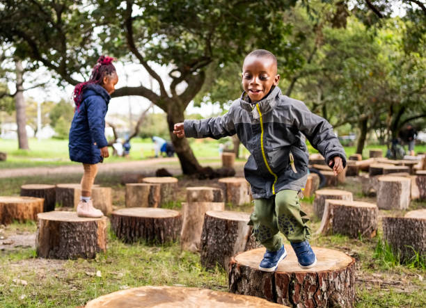 istock Happy little boy jumping on a tree stump at playground 2187741333