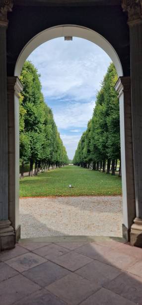 istock An archway into a garden with lawn and many trees in a row 2187747089