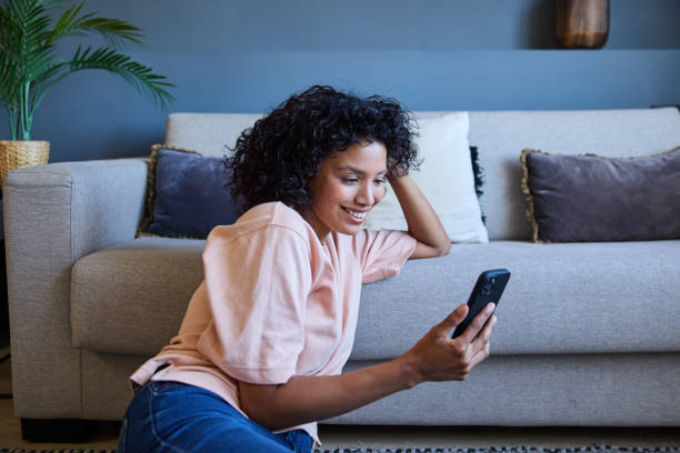 istock Latin woman relaxing on the floor using mobile phone at home 2187751881