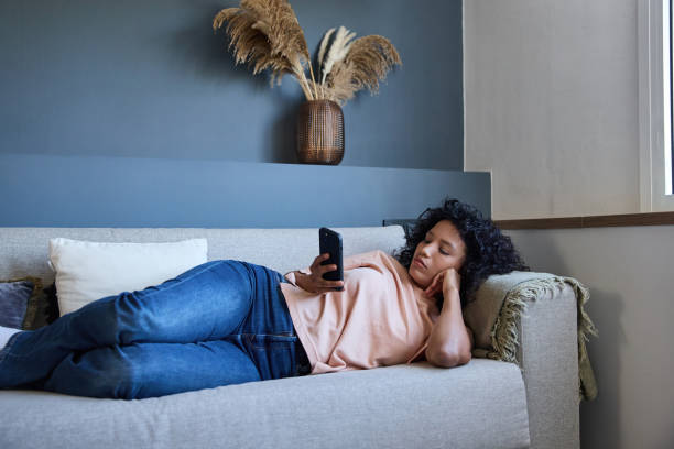 istock Latin woman lying on sofa using smartphone at home 2187751901