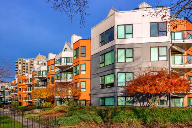 Apartment buildings in downtown of New Westminster City, yellow trees in the courtyard of a residential complex against a blue autumn sky