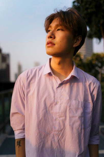Confident young man standing in outdoors. Asian male student looking away while standing outside.