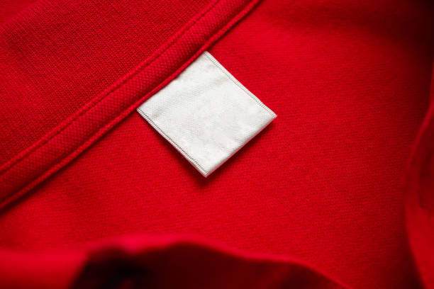 istock Blank white laundry care clothes label on red shirt fabric texture background 2187763293