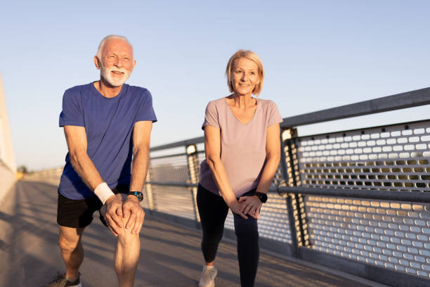 istock Cheerful elderly couple stretches on bridge in morning light 2187763444