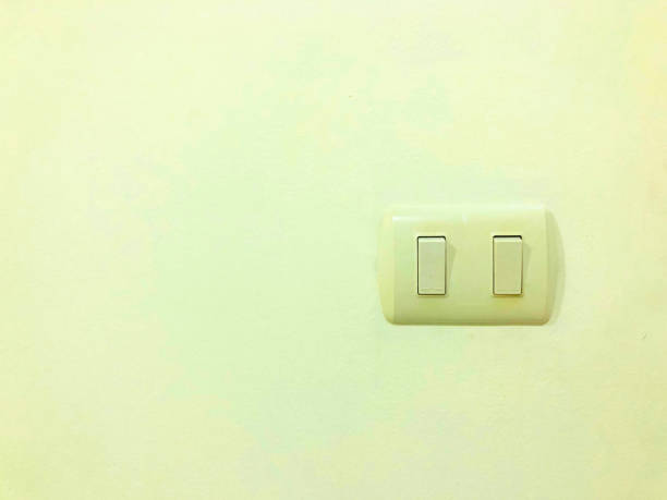 istock A clean dual light switch mounted on a plain yellow wall, offering a minimalist and functional interior design element. 2187763719