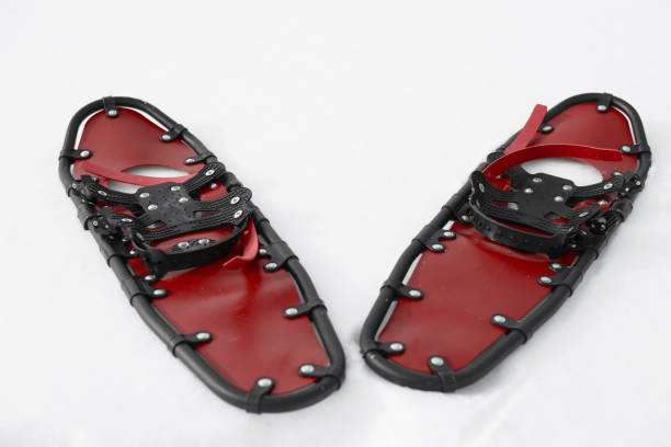 young sportsman walks in red snowshoes and leggings on snow, close-up view of legs, winter hiking concept, active lifestyle