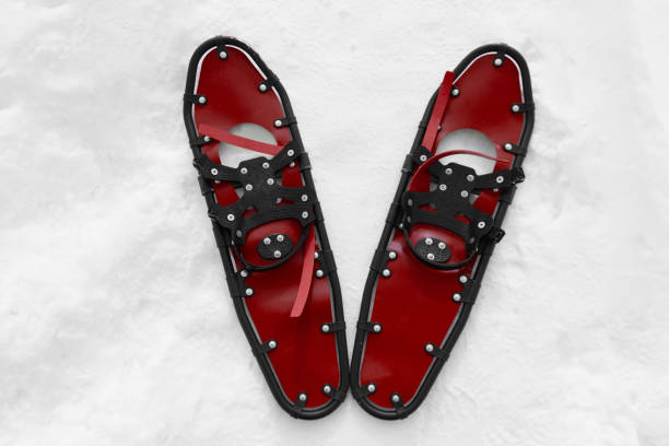 young sportsman walks in red snowshoes and leggings on snow, close-up view of legs, winter hiking concept, active lifestyle