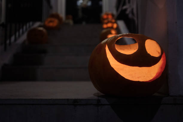 Carved pumpkin with a cheerful face illuminates a staircase, setting a spooky scene for halloween