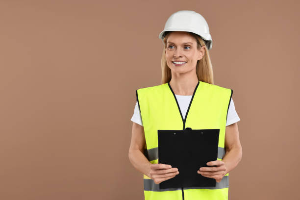istock Engineer in hard hat holding clipboard on brown background, space for text 2187765148