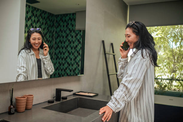 istock Joyful Asian Woman on Phone Call in Bathroom Setting 2187765779