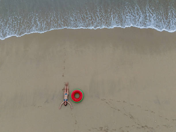 istock Woman Relaxing on Sandy Beach with Inflatable Ring 2187765908