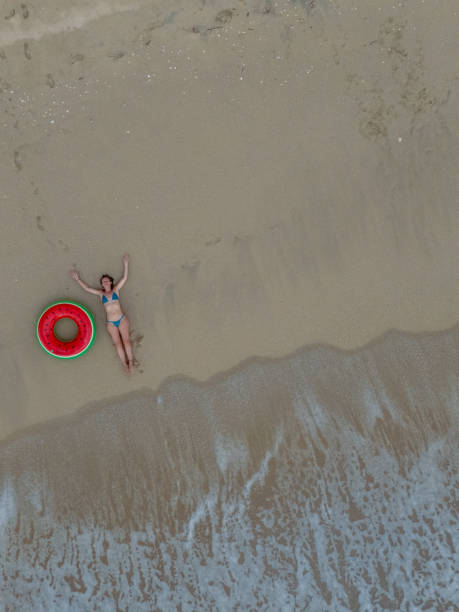 istock Woman Relaxing on Sandy Beach with Inflatable Ring 2187765917