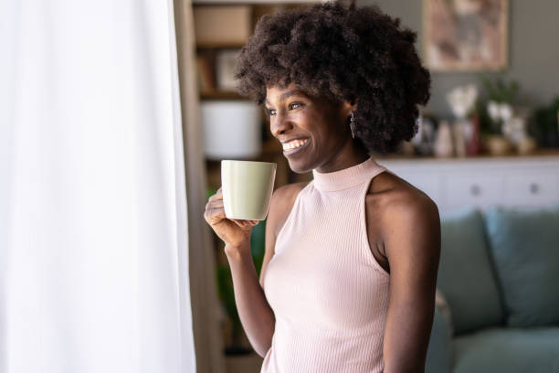 istock Woman enjoying a cup of coffee while standing by a window 2187765989