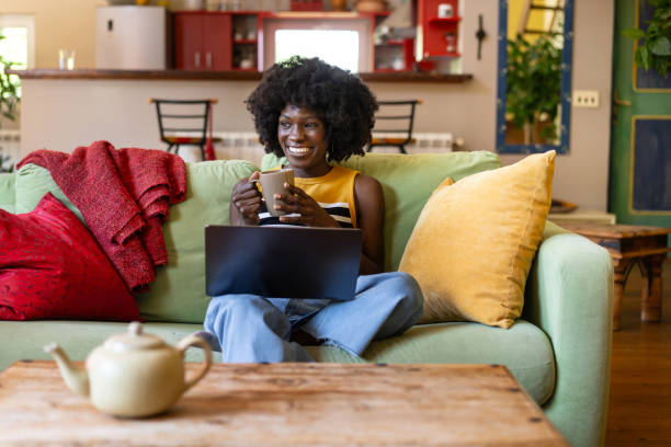 istock A woman drinking tea from a mug, with a laptop on her lap 2187766015