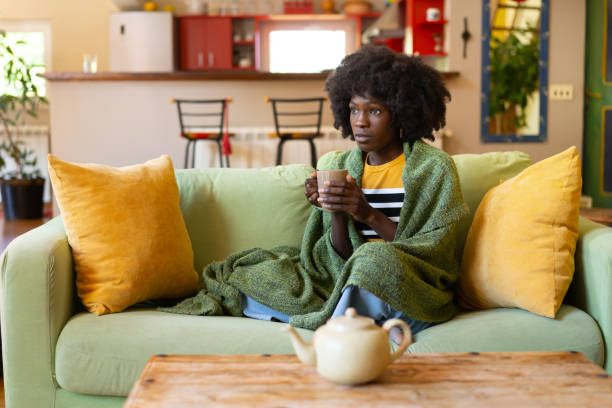 istock A cold woman wrapped up in a blanket on a sofa 2187766026