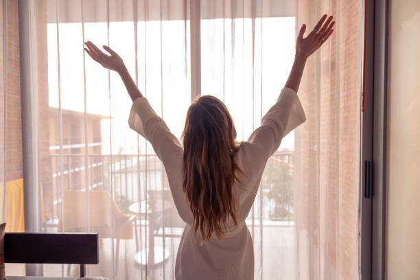 istock Woman Stretching in Morning Light by Window 2187766870