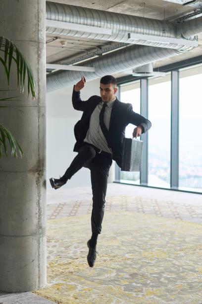 istock A businessman ecstatically jumping in a modern office, holding a briefcase in his hands, celebrating a moment of success and triumph. 2187774088