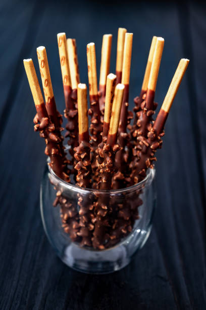 Chocolate Pocky Sticks with Nut Topping on a Dark Wooden Background