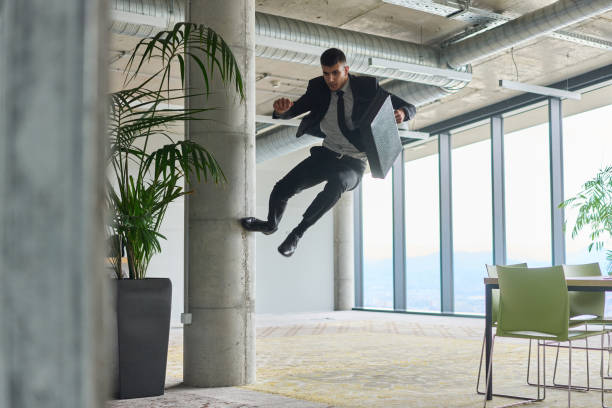 istock A businessman ecstatically jumping in a modern office, holding a briefcase in his hands, celebrating a moment of success and triumph. 2187779399
