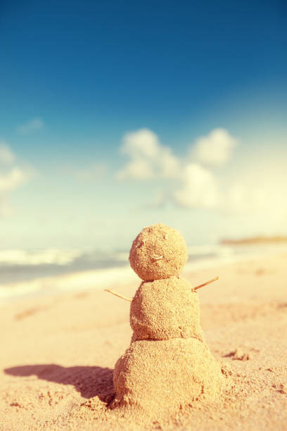 Christmas Snowman made out of sand on sandy beach. Holiday vacation in hot countries concept. New Year travel greeting card with copy space
