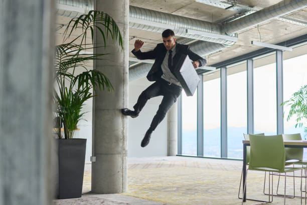 istock A businessman ecstatically jumping in a modern office, holding a briefcase in his hands, celebrating a moment of success and triumph. 2187780095