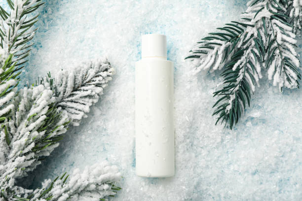 istock Cosmetic bottle, fir branches and snow on light background, top view 2187780120