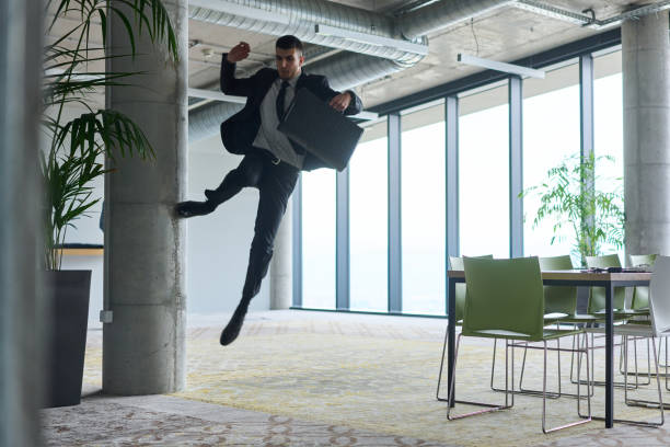 istock A businessman ecstatically jumping in a modern office, holding a briefcase in his hands, celebrating a moment of success and triumph. 2187780239