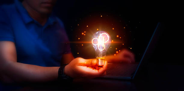 istock Man using laptop and holding illuminated light bulb with gear shine glitter represent Idea success, innovation and inspiration concept. 2187782492