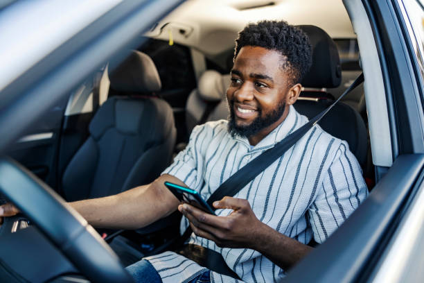 istock Young interracial man is driving a car and using cellphone for GPS in traffic. 2187789884