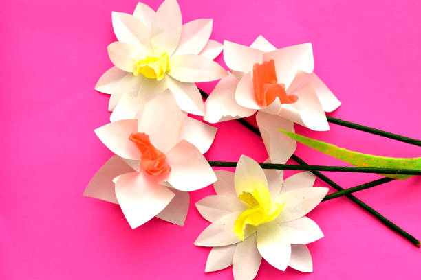 Origami. Ideas for children's development. Paper flowers made by children's hands on a colored background.