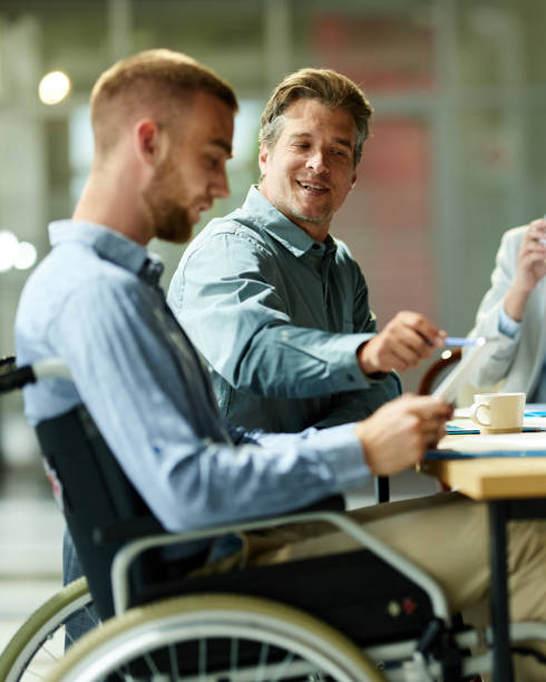 istock Happy businessman using touchpad with his disabled colleague on a meeting. 2187795926