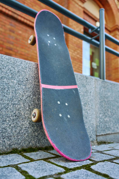 istock Used pink skateboard against stone wall in urban setting 2187796612