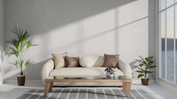 istock A minimalist white living room featuring a comfortable beige couch, a coffee table, and houseplants. 2187796700