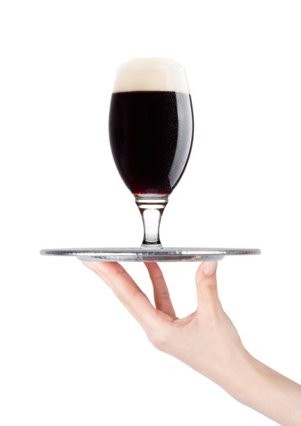 Hand holds tray with cold stout dark beer with dew stock photo