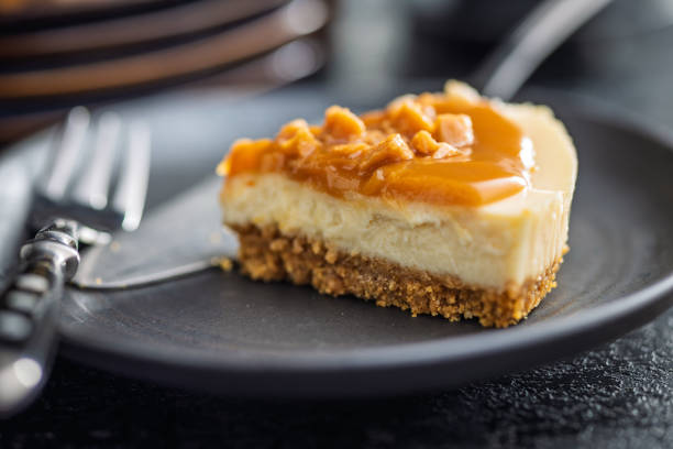 istock A cut piece of cheesecake with caramel topping on plate on black table. 2187796868
