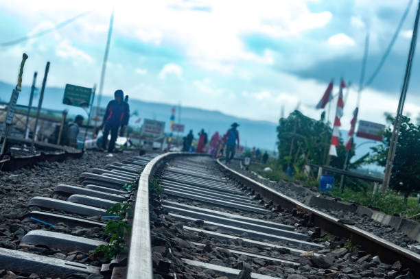 Scenic railway track with people walking, lush greenery, and vibrant flags under a bright sky. Perfect for travel, adventure, and lifestyle themes