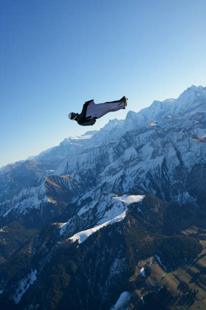 istock Wingsuit flier soars on his back above snowcapped mountains 2187797868