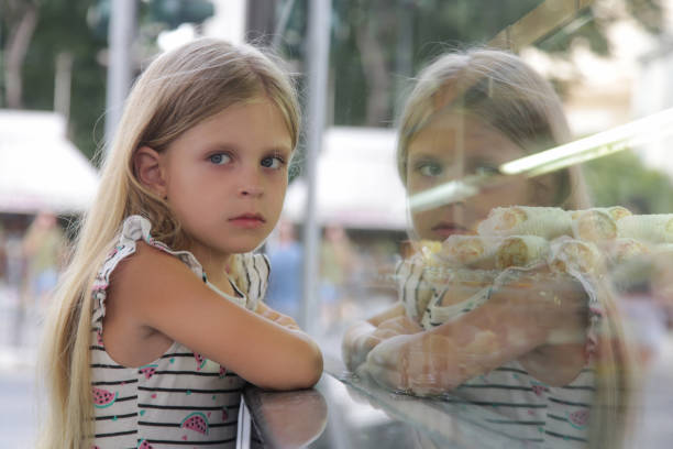 istock Grumpy and sad little girl looking at a cake store window 2187797874