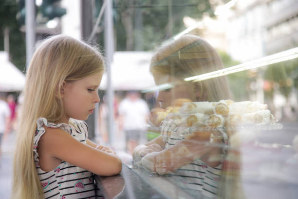 istock Grumpy and sad little girl looking at a cake store window 2187798088