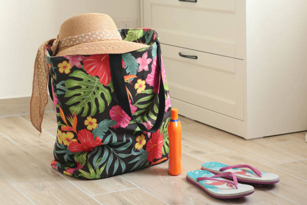 istock Summer hat with bow on beach bag near flip flops at home. 2187803115