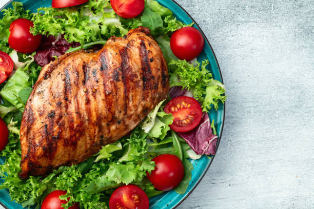 istock Grilled chicken breast ( fillet ) with lattuce salad and cherry tomatoes . Top view 2187803619