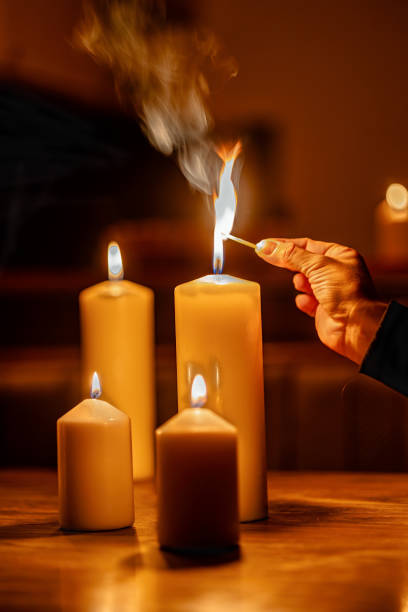 People light candles in a dark room due to power outage while attempting to create warmth and ambiance during the evening
