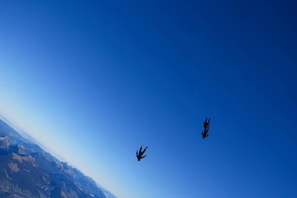 Skydivers soar in blue skies, Kandersteg Valley, Swiss Alps