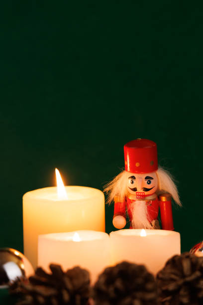 A classic nutcracker with original hair is beautifully displayed with candles on a deep green canvas, radiating holiday cheer and warmth