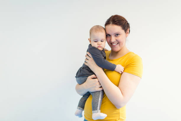 A joyful mother lovingly holds her baby, showcasing a tender moment of parent-child bond with a minimalist background. Perfect for family or motherhood themes.