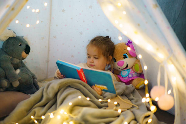 istock A girl looking at a picture book while sitting in a tent 2187809227