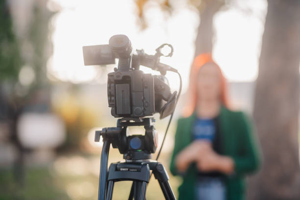 istock Professional video camera recording a journalist making a report in a park 2187810049